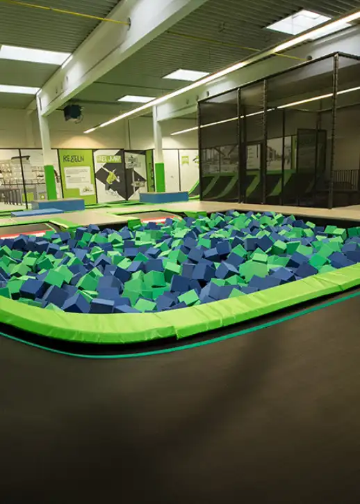 Ein großer Indoor-Trampolinpark mit grünen und schwarzen Matten, ideal für Spaß und Bewegung.