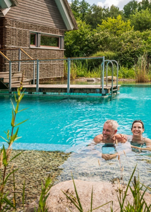 Ein Paar schwimmt im Wasser eines Resorts und erfreut sich an der romantischen Atmosphäre und der schönen Landschaft.