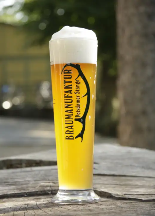 Ein Bierglas steht auf einem Tisch und reflektiert das Licht in einem gemütlichen Ambiente.