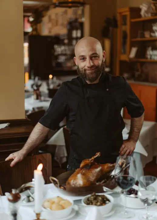 Ein Mann posiert vor einem Tisch, der mit einer köstlichen Gans dekoriert ist.