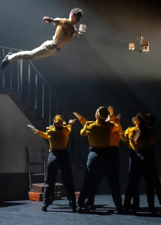 Ein Mann schwebt in der Luft, umgeben von einer Gruppe von Menschen, die begeistert zuschauen. Gutschein für Stories The Tap Dance Sensation.