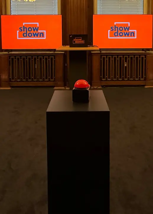 Zwei große Bildschirme mit dem Schriftzug "your Showdown" und einem roten Button zum quizzen.