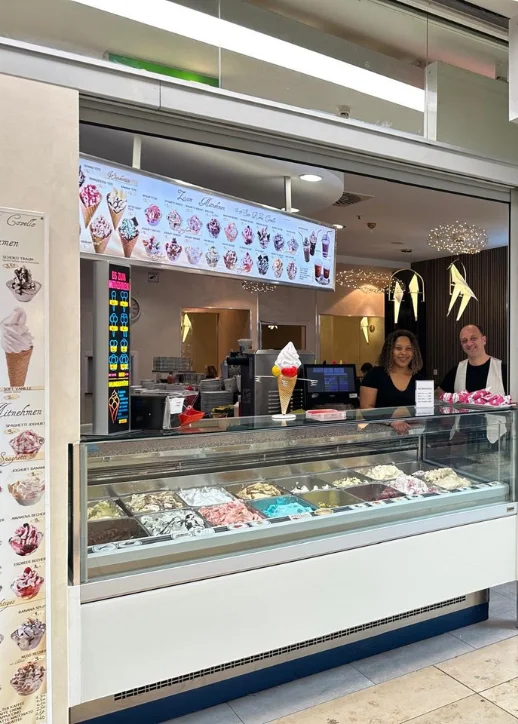Im Eiscafé "San Remo" steht eine Frau hinter dem Tresen und bietet verschiedene Eissorten an.