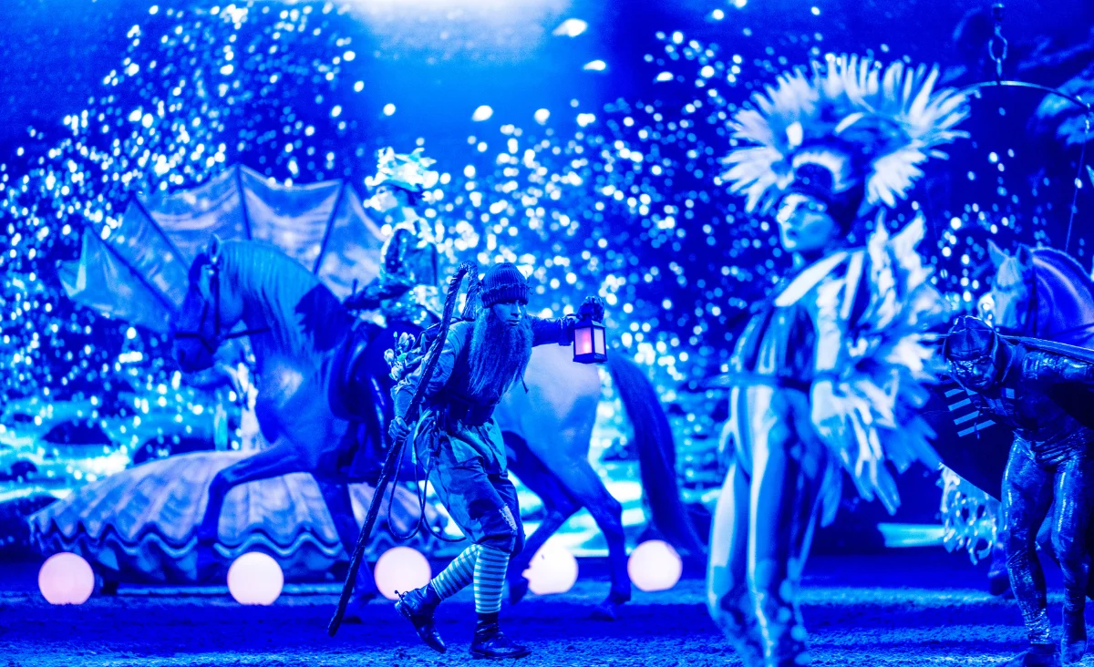 Eine Gruppe von Menschen in bunten Kostümen steht auf einer Bühne während der CAVALLUNA-Show in Berlin.