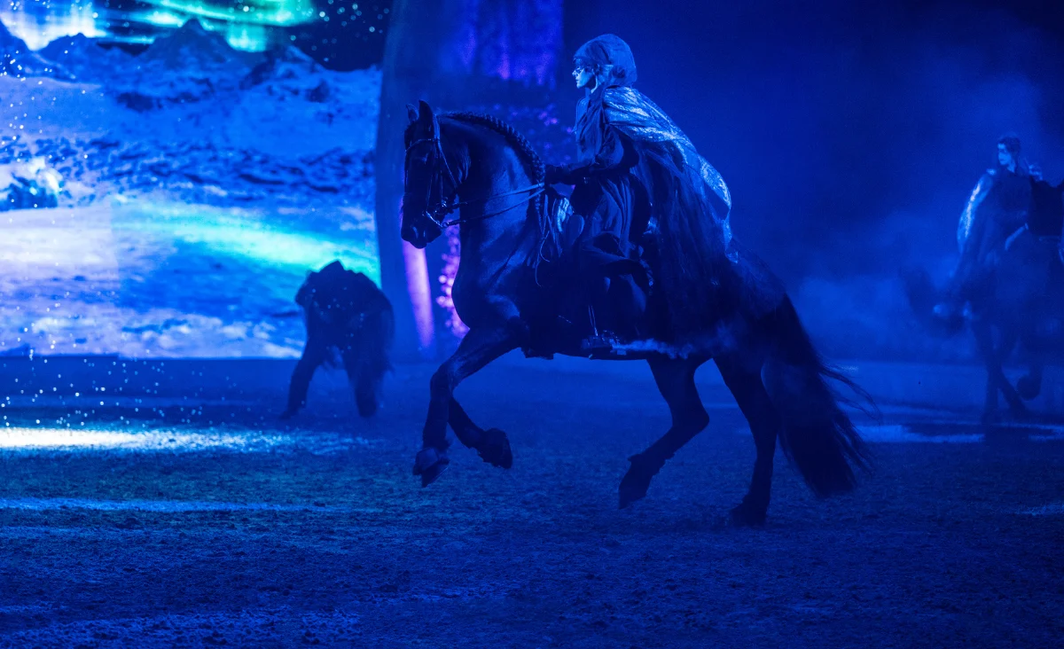 Ein Mann reitet auf einem Pferd in einer dunklen Arena während der CAVALLUNA-Show in Berlin.