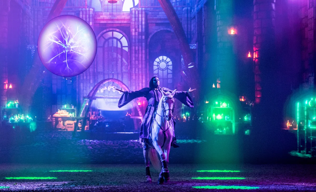 Ein Mann in einem Kostüm steht vor der Bühne der CAVALLUNA-Show in Berlin, die magische Abenteuer verspricht.