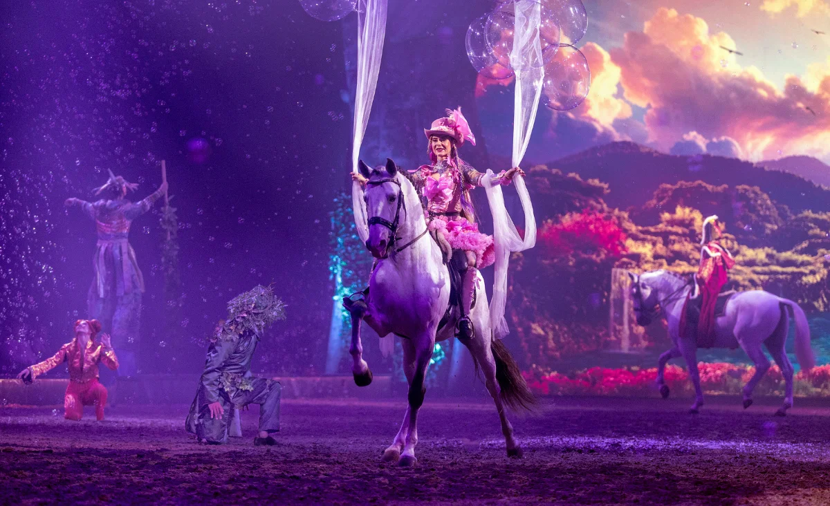Eine Frau und ein Mann reiten auf Pferden, umgeben von einer fantastischen Kulisse, die die Magie der CAVALLUNA-Show widerspiegelt.