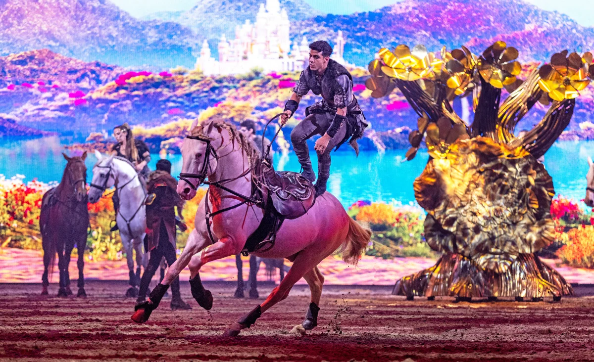 Ein Mann reitet auf einem Pferd vor einer großen Leinwand, die die spektakuläre Show CAVALLUNA in Berlin bewirbt.