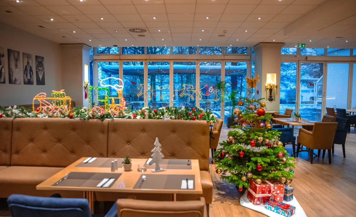 Restaurant im Hotel Müggelseeperle mit Weihnachtsbaum und festlich dekoriertem Tisch.
