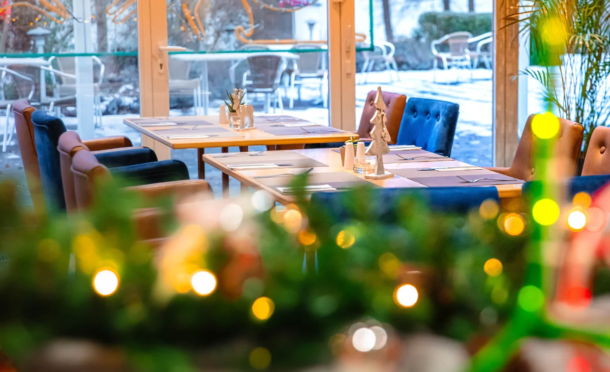 Restaurant im Hotel Müggelseeperle in Berlin-Köpenick mit Tischen und Stühlen vor einem großen Fenster.