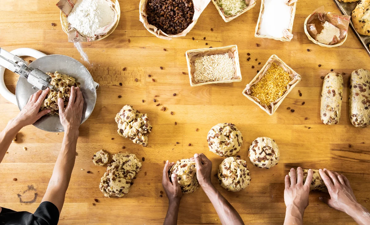 Hände greifen nach Stollen auf einem Holztisch in der Stollenbäckerei Krause in Dresden.