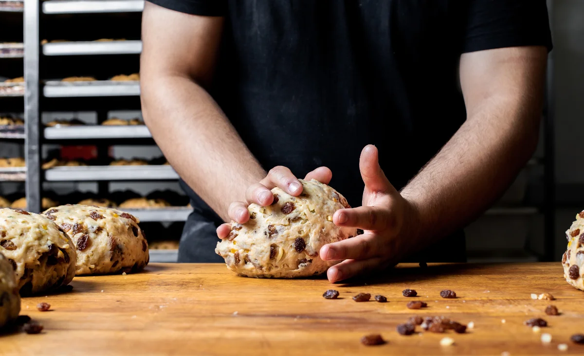 Ein Mann legt ein Stück Brot auf einen Tisch in der Stollenbäckerei Krause in Dresden.
