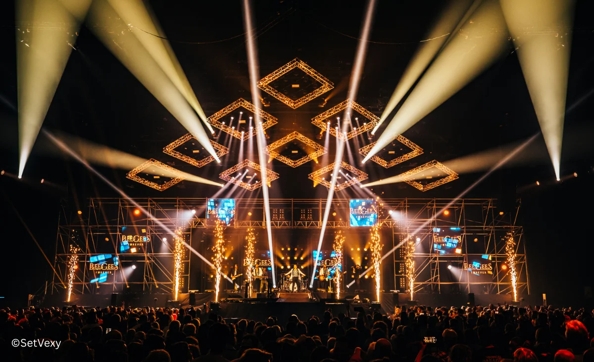 Bühne mit Lichtern und Menschen im Hintergrund während des Bee Gees Konzerts von Maincourse im Tempodrom Berlin.