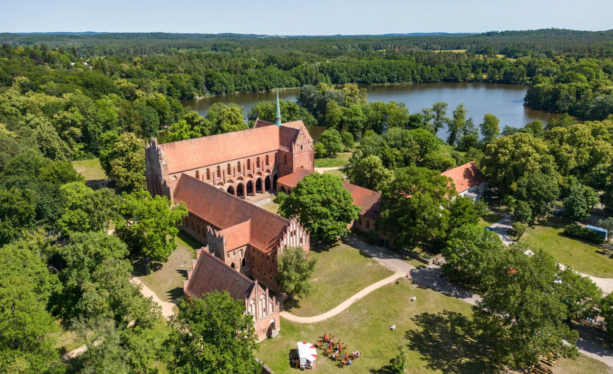 Luftaufnahme einer Kirche und eines Sees inmitten eines Waldes, auf einer der deutschen Ostseeinseln.