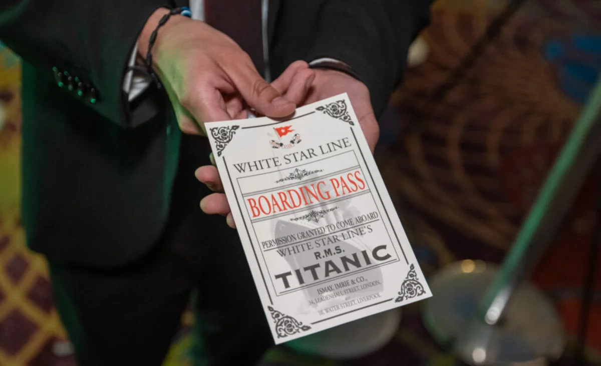 Ein Mann im Anzug hält ein Ticket für die Titanic-Ausstellung in der Hand.