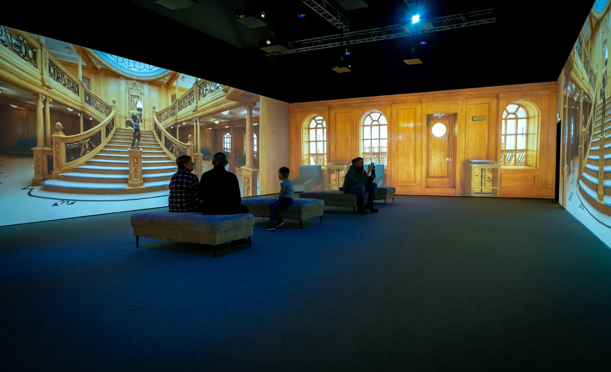 Besucher schauen auf eine große Projektion eines Raums, das zur Ausstellung "Titanic" gehört.