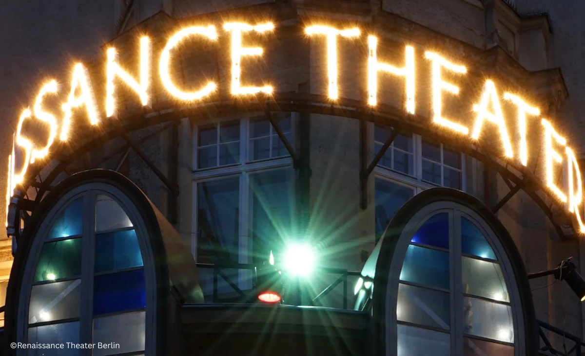 Leuchtende Schrift 'RENAISSANCE THEATER' über einem Bogenfenster mit Spiegelungen und Lichtreflexen