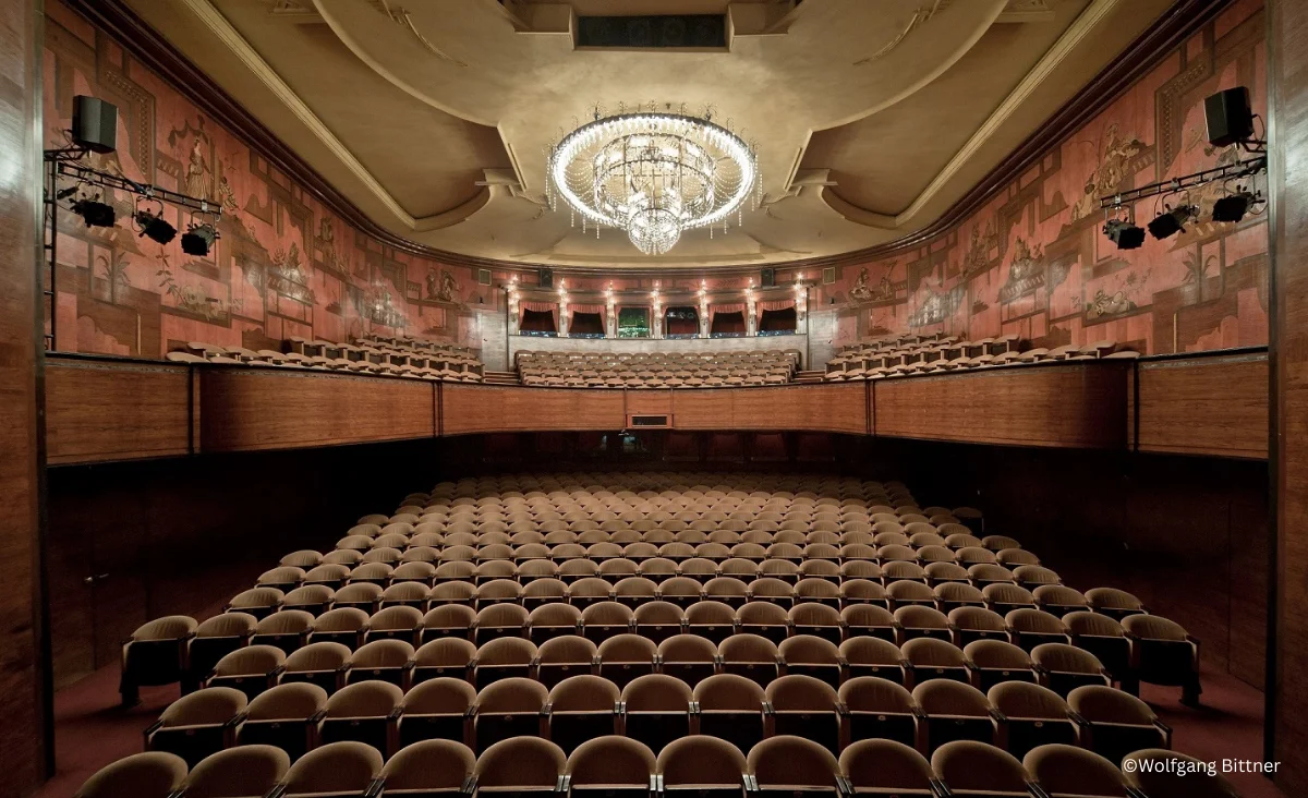 Innenansicht des Renaissance Theaters Berlin mit Reihen von Sitzplätzen und einem prunkvollen Kronleuchter an der Decke