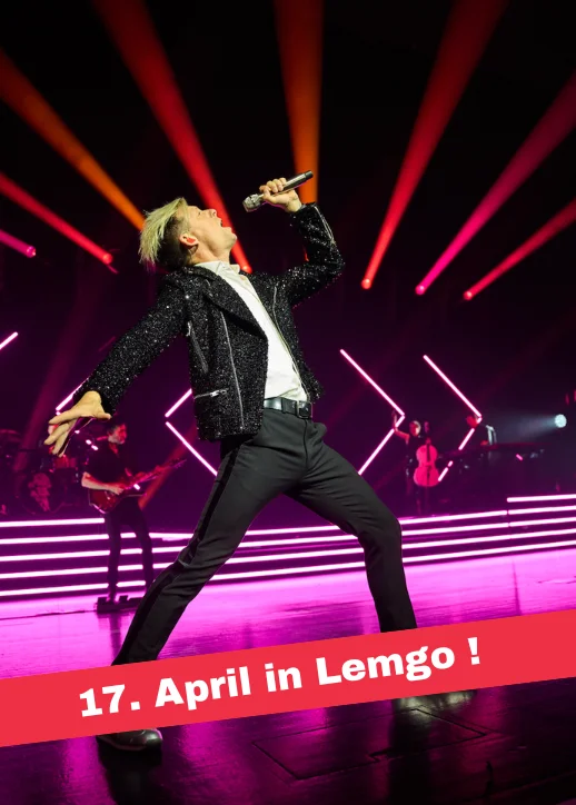 Ein Mann in schwarzer Jacke singt auf der Bühne während der Symphonic Evolution Tour.