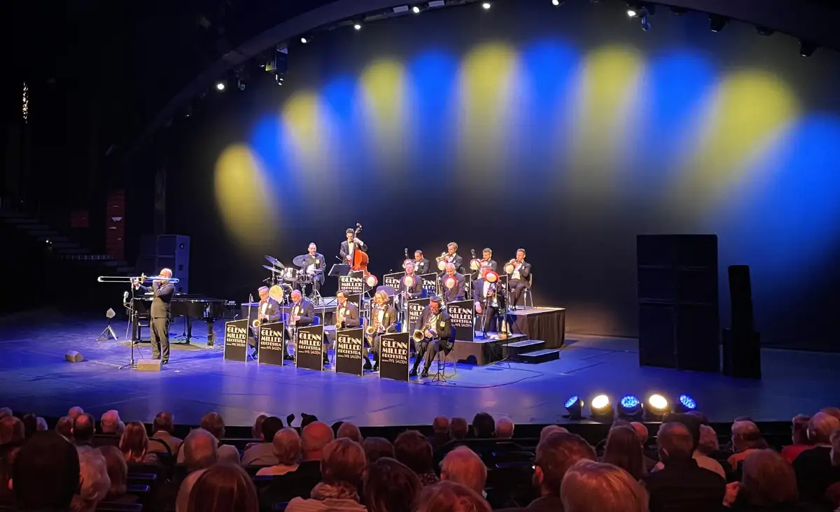Glenn Miller Orchestra live auf der Theaterbühne mit blau-gelber Beleuchtung vor Publikum