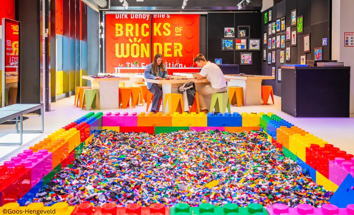 Zwei Personen sitzen an einem Tisch in einem Raum mit bunten LEGO-Steinen bei Bricks of Wonders.