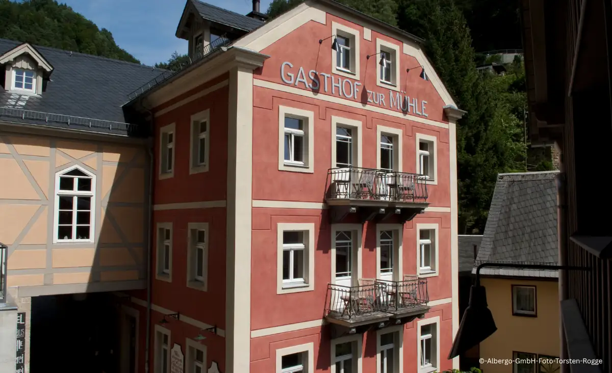 Fassade des Gasthofs Zur Mühle mit Balkonen und Schriftzug in einem Dorf mit Fachwerkhäusern