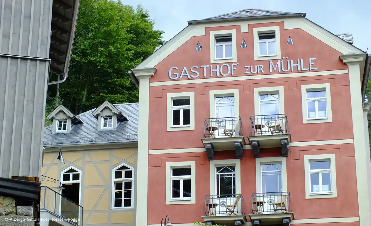 Fassade des Gasthofs Zur Mühle mit Balkonen und Schriftzug in einem Dorf mit Fachwerkhäusern